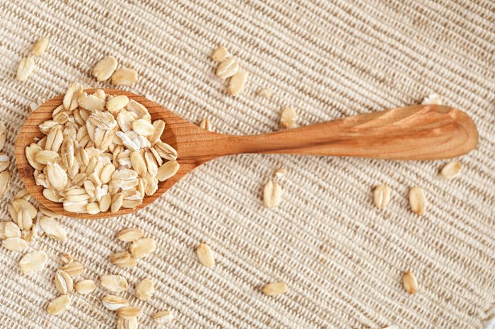 Oatmeal flakes and wooden spoon on fabric