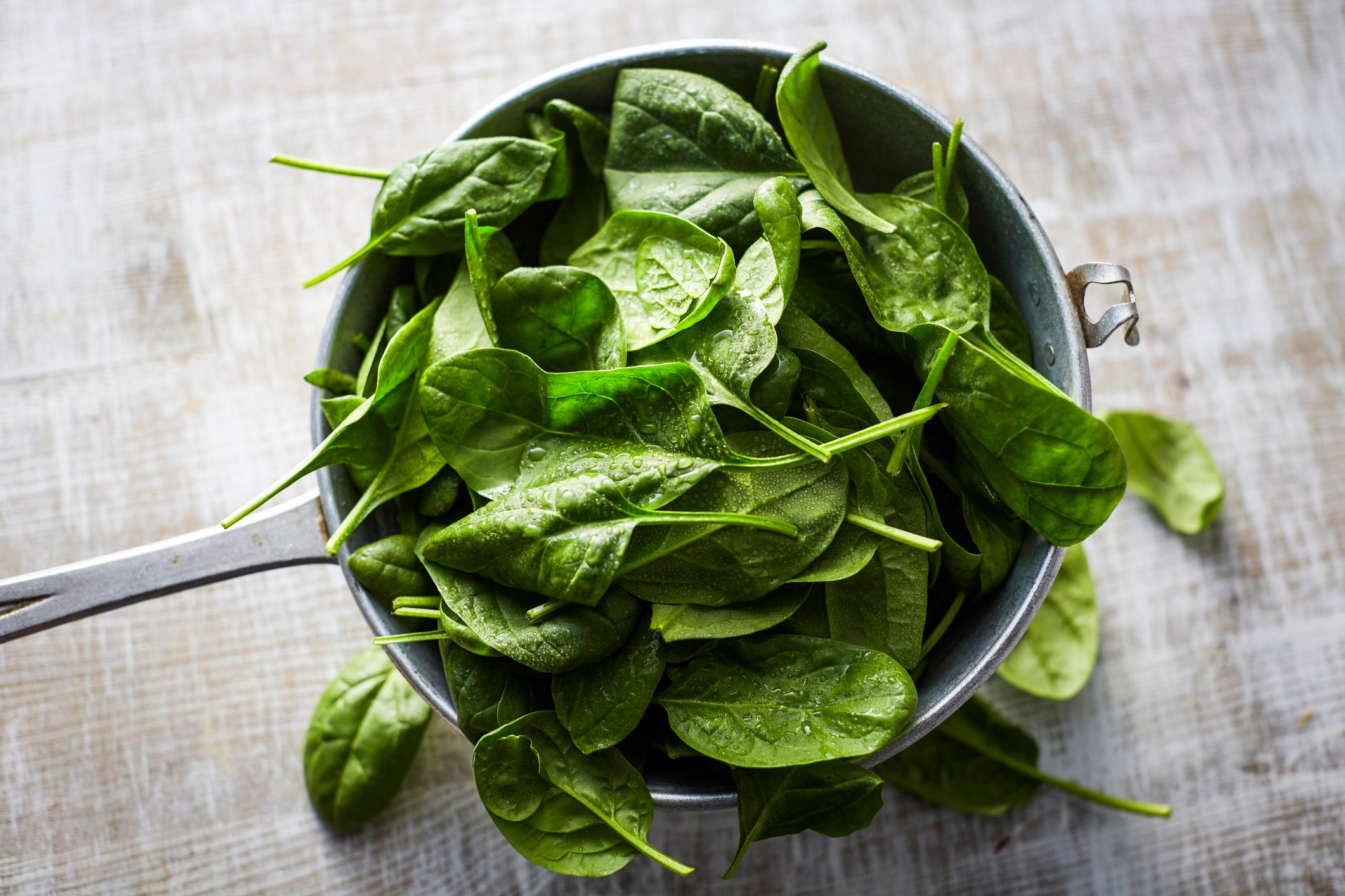 spring vegetables, Fresh spinach leaves in colander on wood