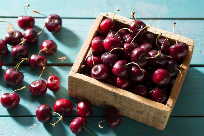 Fresh Bing Cherries In Box On Blue Wood Surface